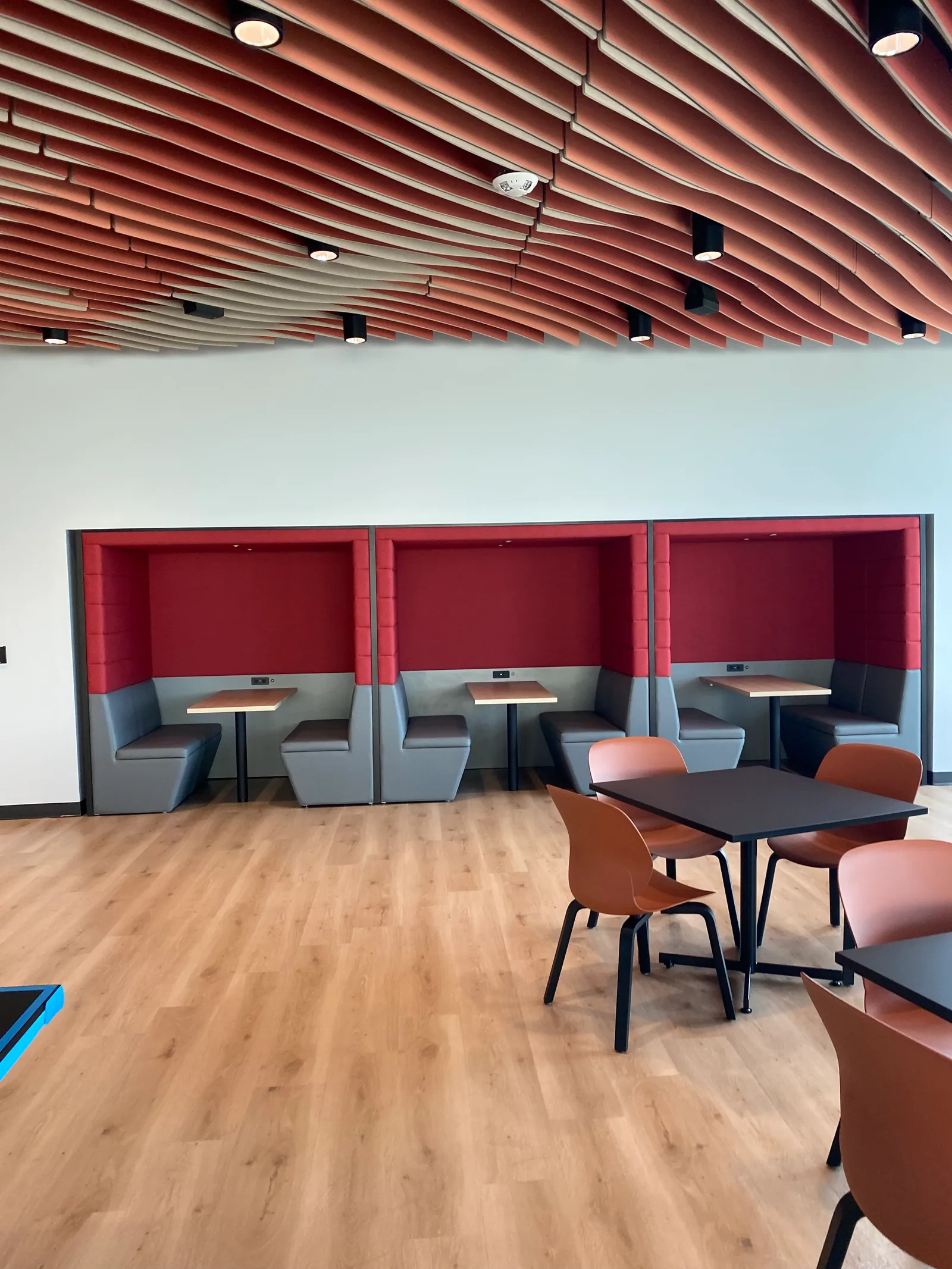 Café seating with red upholstered booths and a timber-slat ceiling.