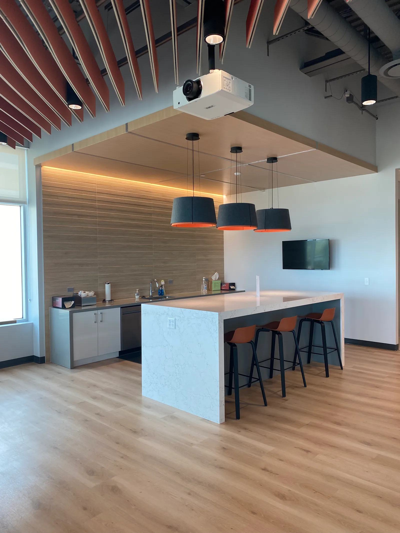 Shared kitchen with a central island, bar stools and pendant lights.