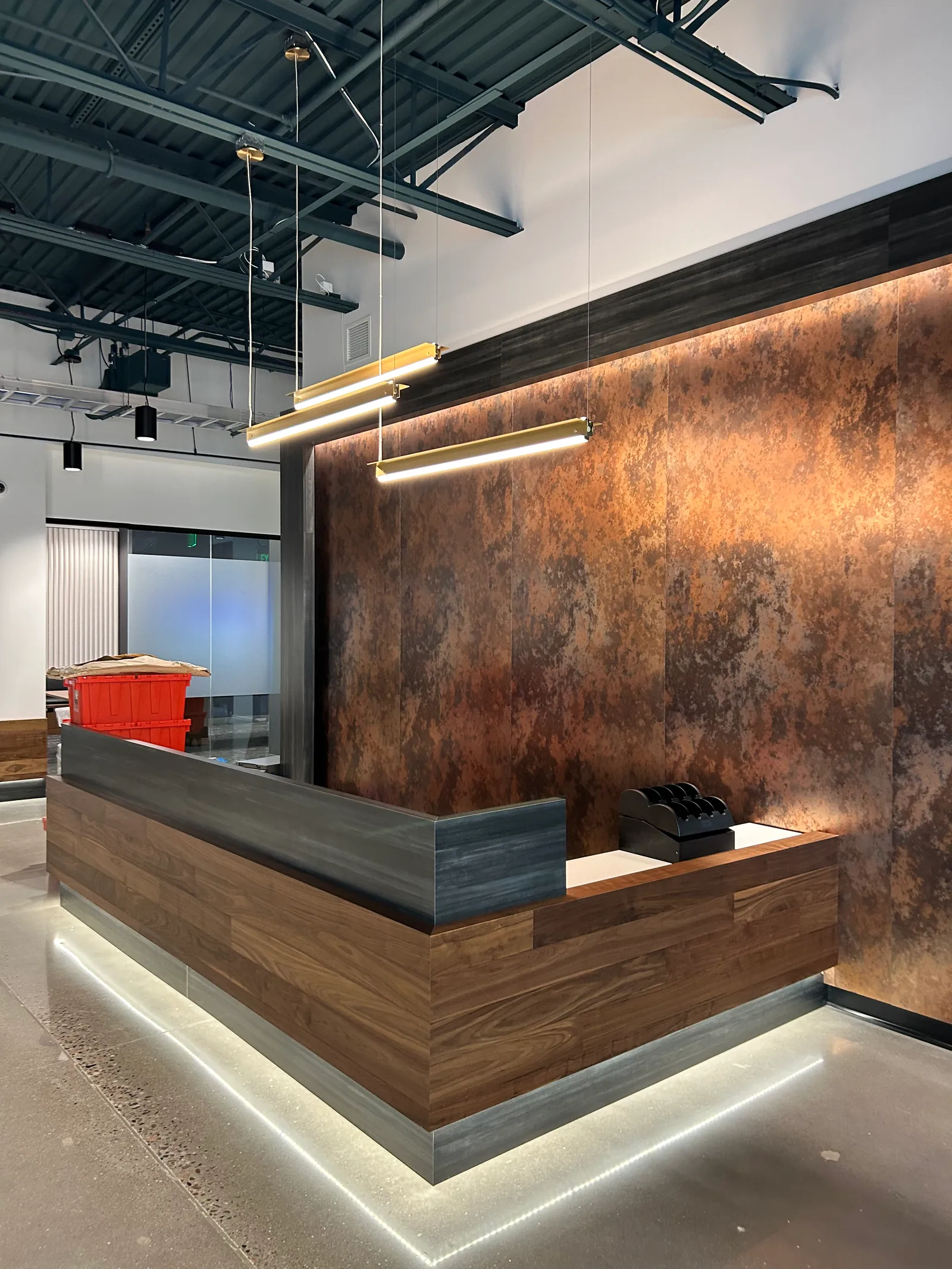 Reception desk with timber cladding and a textured metal feature wall.