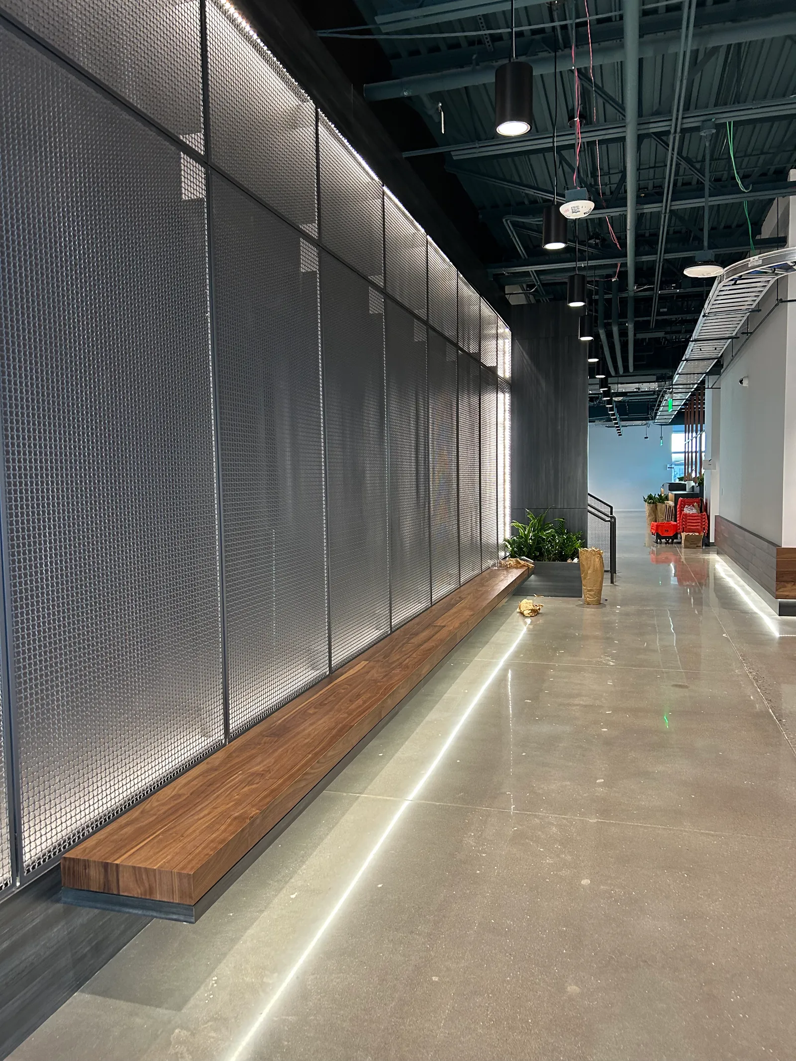 Workplace corridor with perforated wall panels and a long timber bench.