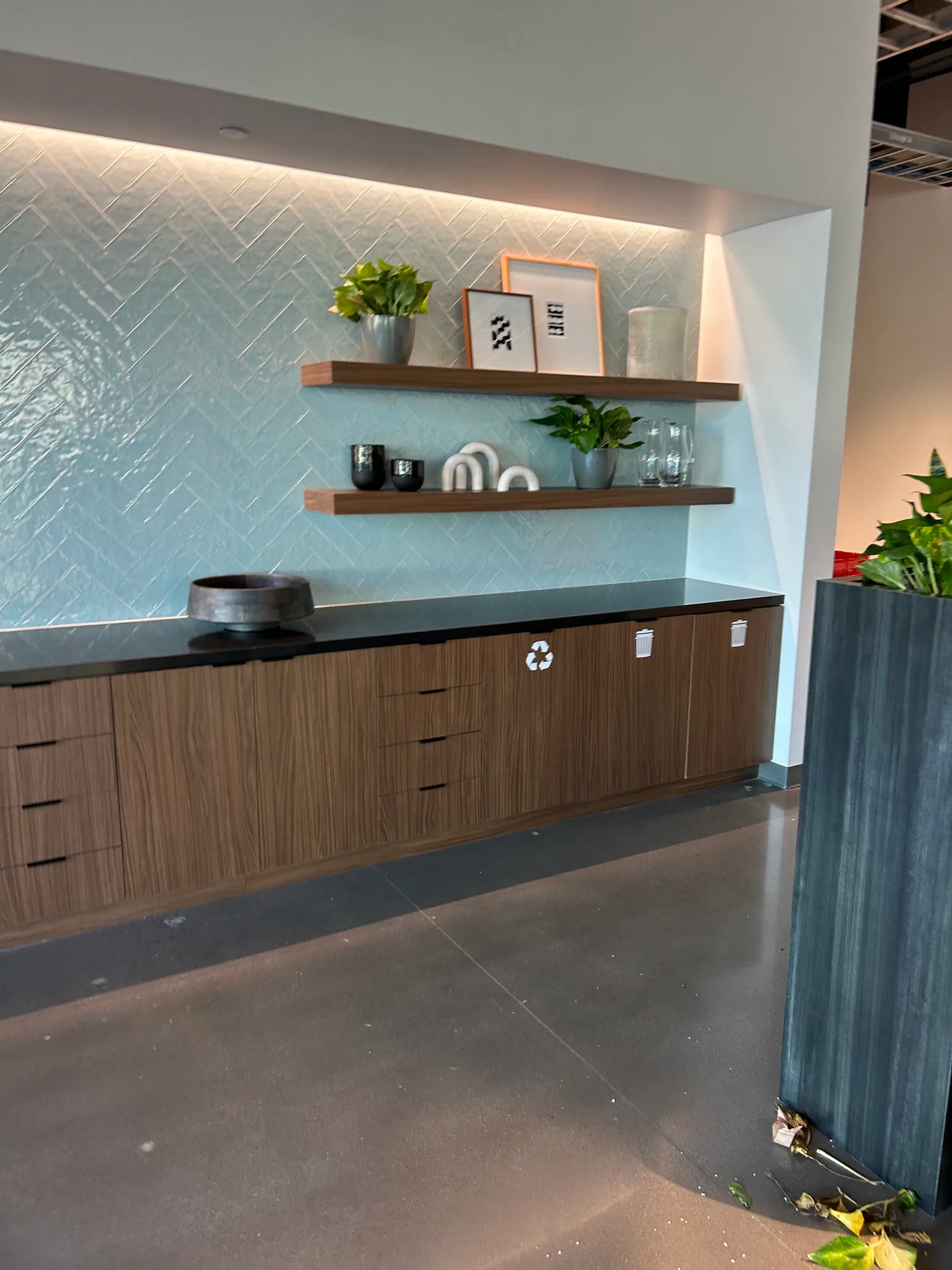 Refreshment counter with blue tile, open shelves and integrated waste stations.