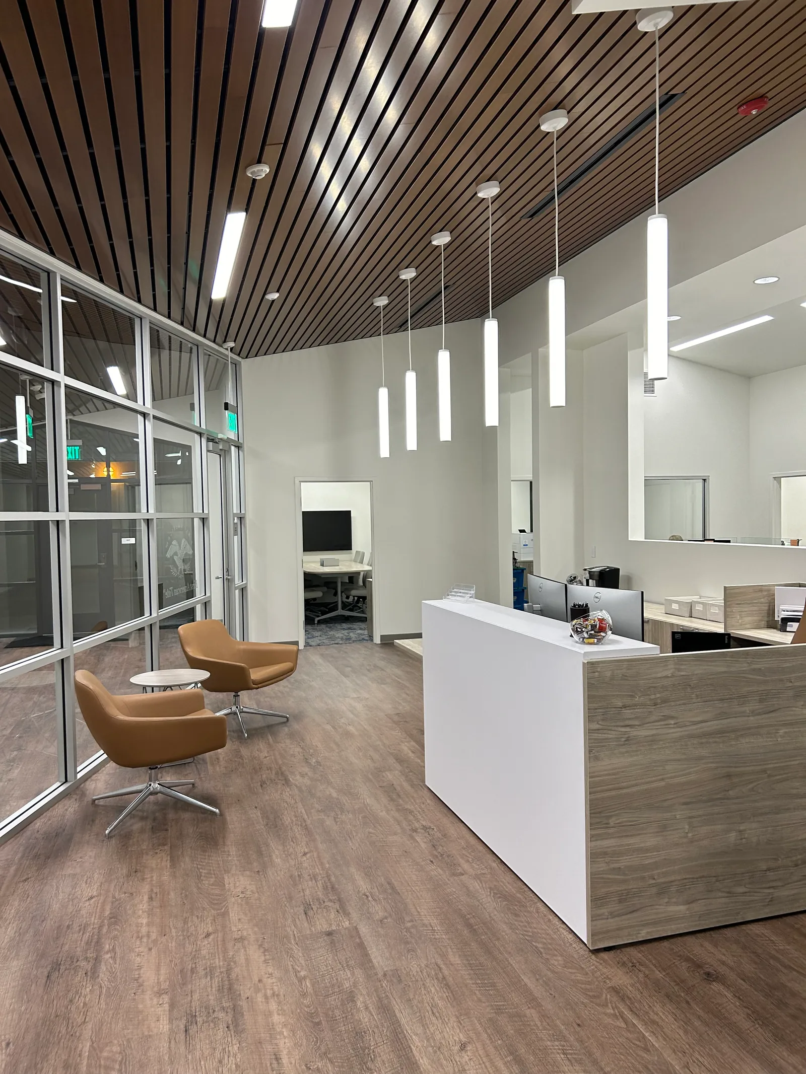 Reception counter and waiting chairs beneath suspended white lights.