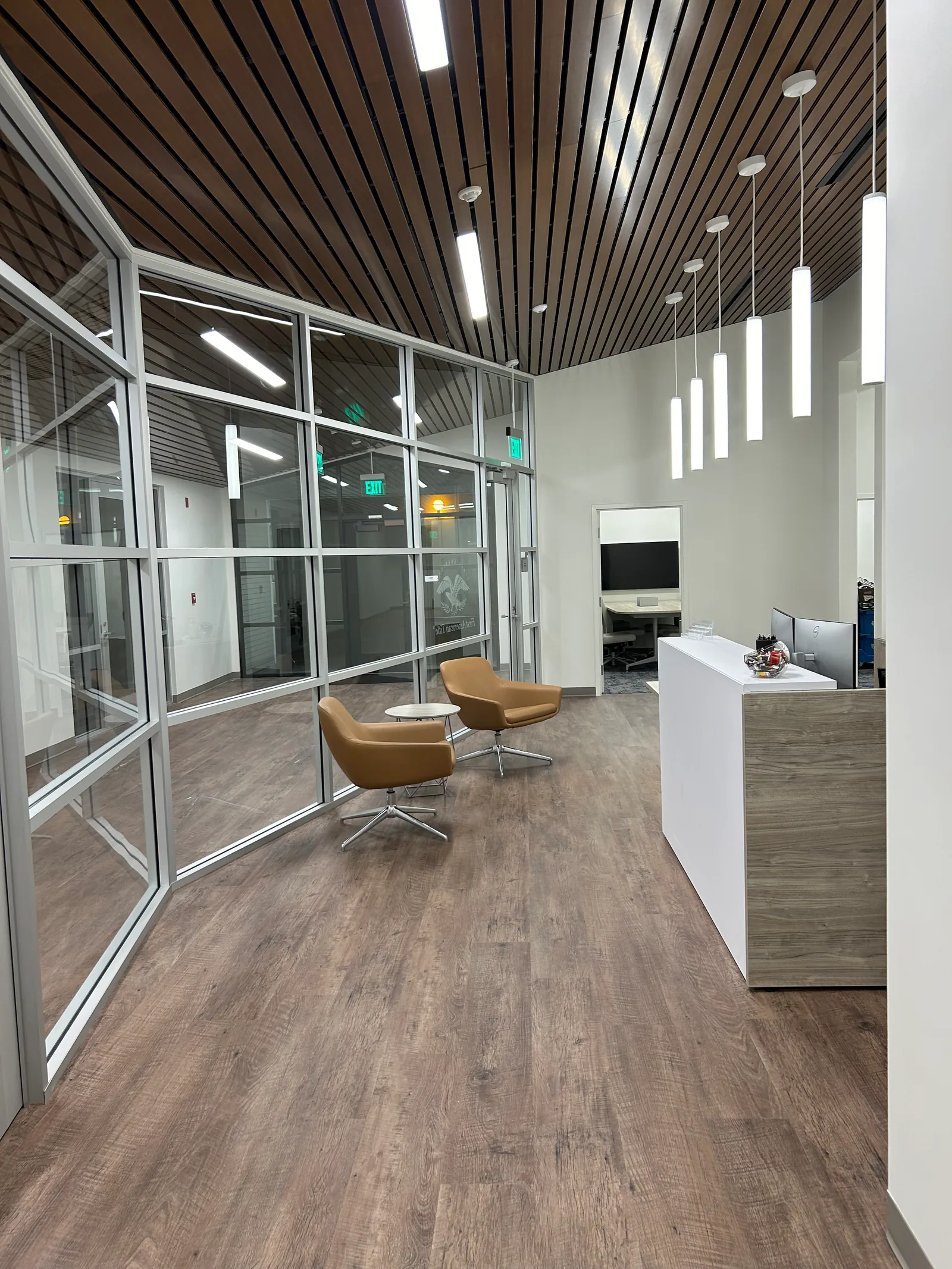 Waiting area beside full-height glass partitions and the reception counter.