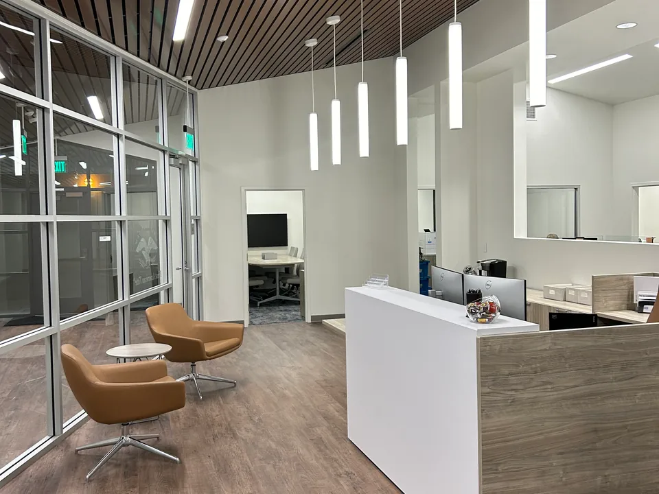 Reception counter and waiting chairs beneath suspended white lights.