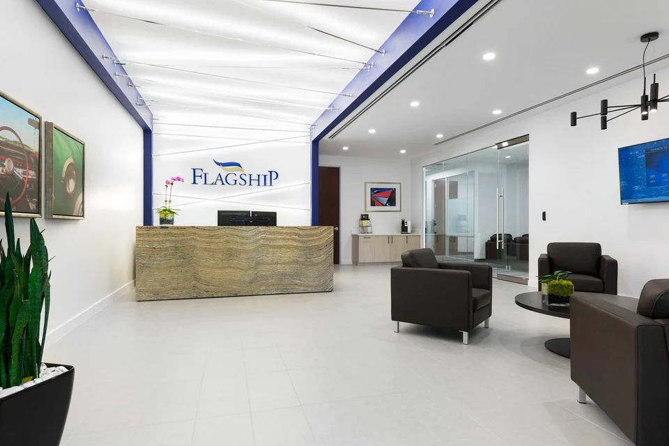 Flagship reception with a stone-front desk and a softly illuminated white ceiling.