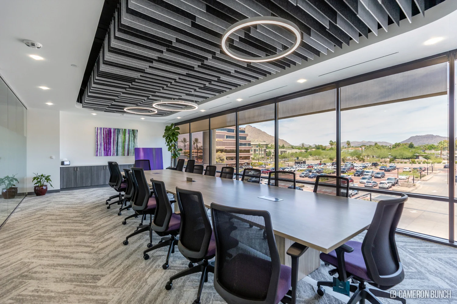 Glass-enclosed boardroom with a long table and mountain views.