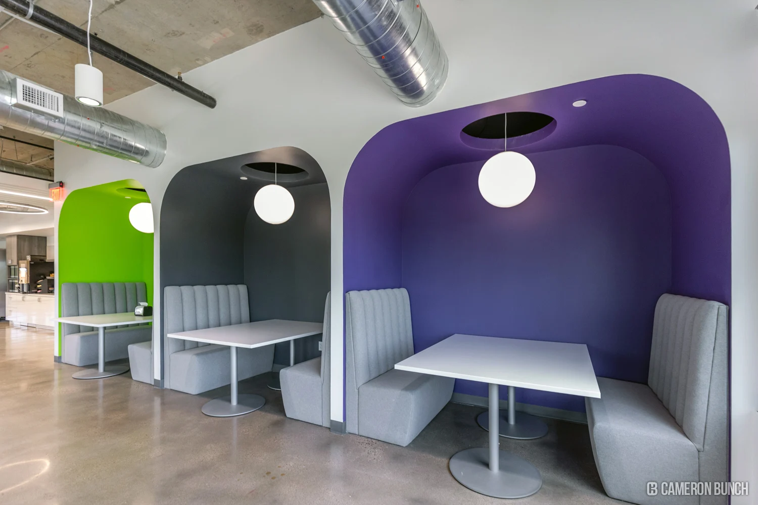 Upholstered meeting booths in green, charcoal and purple.