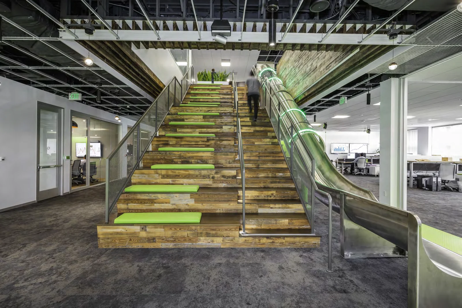 Central timber staircase and slide connecting workplace levels.