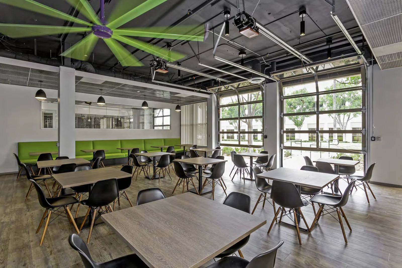 Staff café with shared tables and a large green ceiling fan.