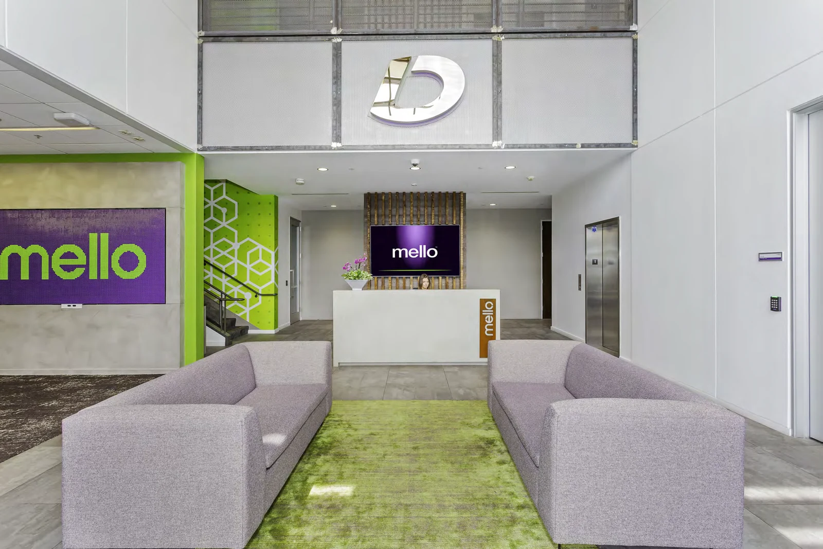 Front view of Mello reception, with pale upholstered sofas and green brand details.