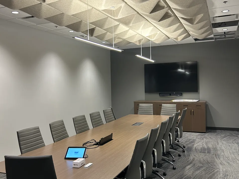 Boardroom with a long timber table, acoustic ceiling panels and a wall-mounted display.