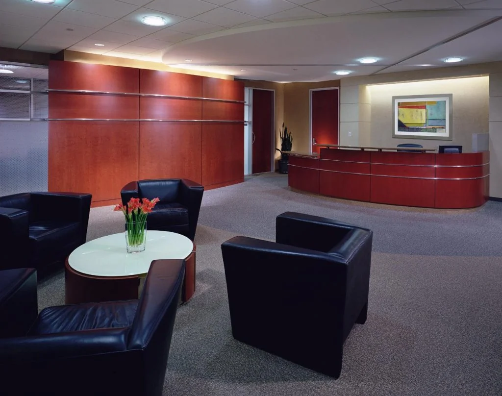 Reception lounge with red-toned timber and soft seating.
